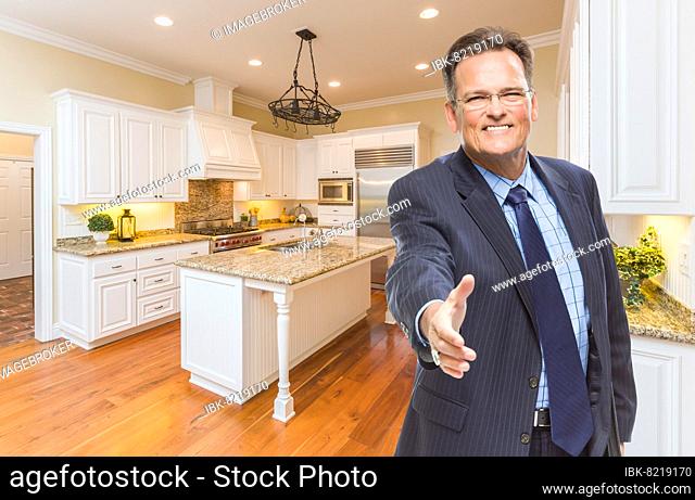 Smiling male agent reaching for hand shake in beautiful new kitchen