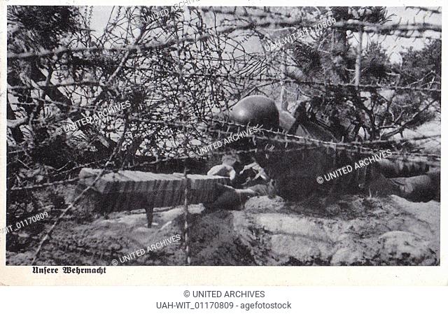 Ein Soldat der Wehrmacht beim Pionierdienst, ein Schützengraben wird mit Stacheldraht gesichert