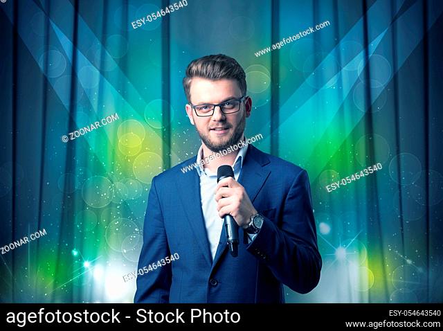 Businessman speaking into microphone with blue curtain behind him