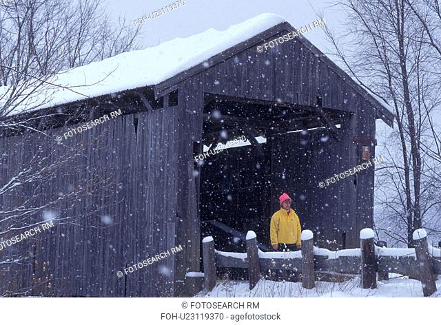 covered bridge, winter, Vermont, A woman walks across the Scribner or Mudget Covered Bridge on a snowy wintry day in Johnson in Lamoille County in the state of...