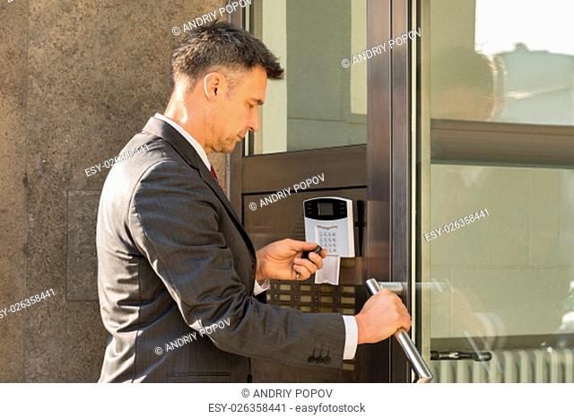 Close-up Of Businessman Using Remote Control For Operating Door Security System