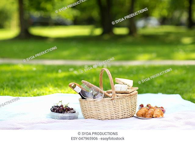 picnic basket, food and wine at summer park
