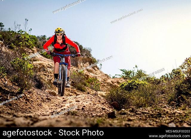 Female moutainbiker riding down dirt track, Fort Ord National Monument Park, Monterey, California, USA