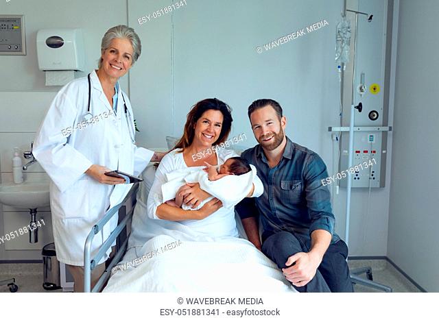 Couple with doctor holding their newborn baby in the ward
