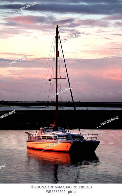View of a private anchored boat at calm sunset