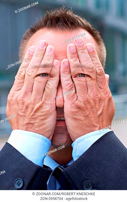 Geschäftsmann mit Händen und Augen vor seinem Gesicht