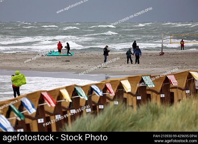 30 September 2021, Mecklenburg-Western Pomerania, Wustrow: Walkers are out and about on the whipped-up Baltic Sea. Gale-force winds up to force 9 cause spray...