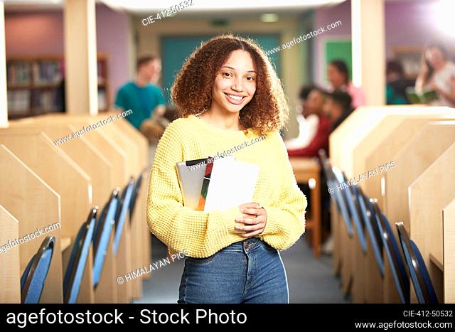 Portrait confident smiling young female college student in library