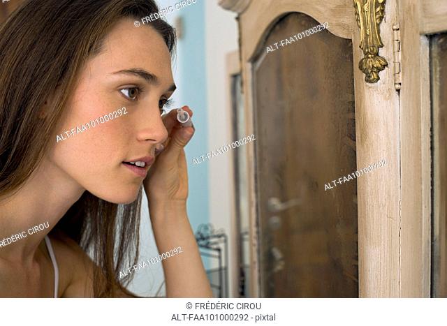Woman putting on mascara