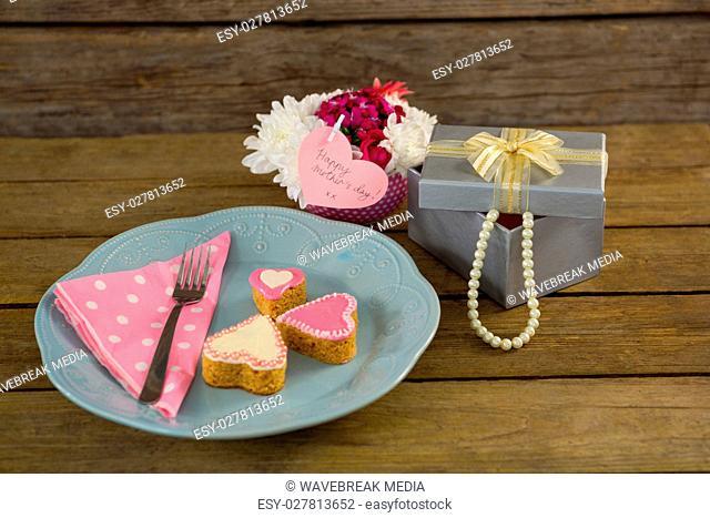 Open gift box with flower vase and heart shape cookies