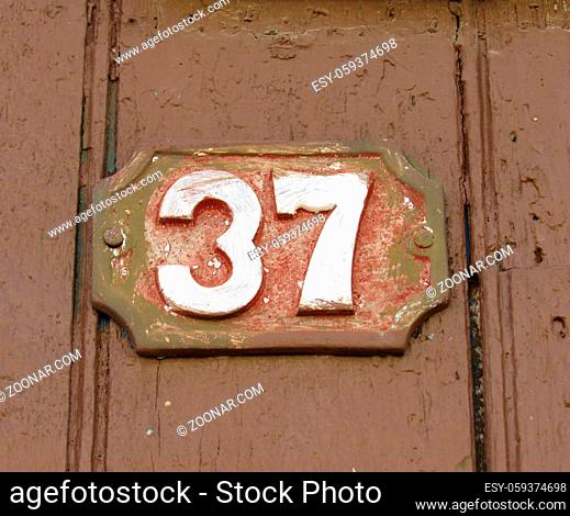 Vintage grunge square metal rusty plate of number of street address with number. Close up, brand