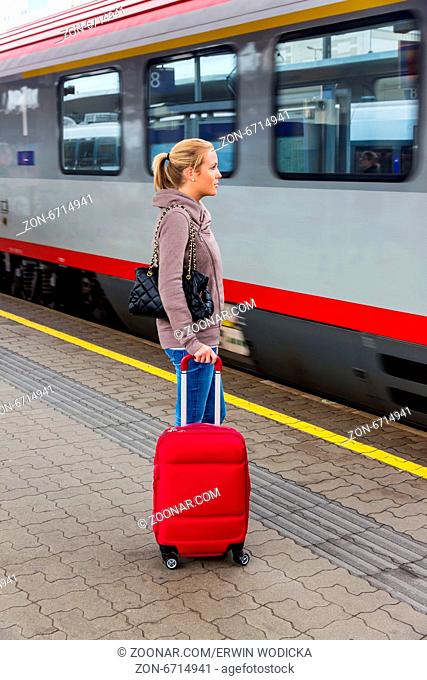 Eine junge Frau wartet auf einen Zug in einem Bahnhof. Zugfahrt in den Urlaub