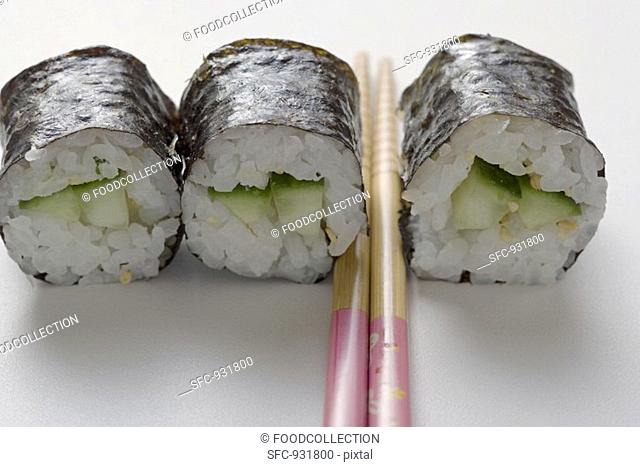 Three maki sushi with cucumber and chopsticks