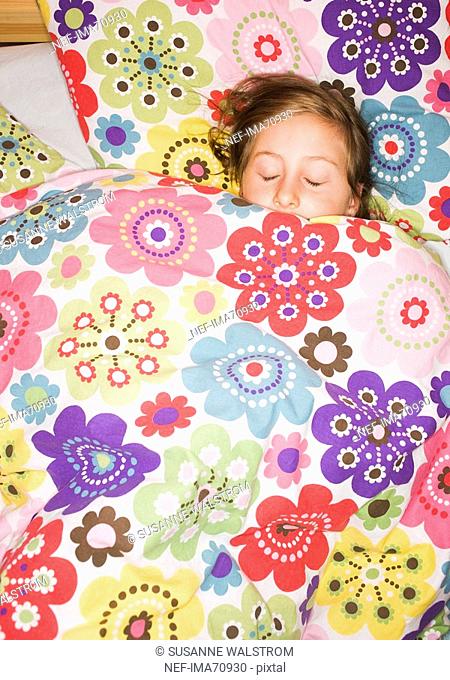 A girl lying under a flowery quilt Sweden