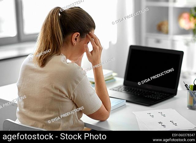 tired teacher with laptop having headache at home