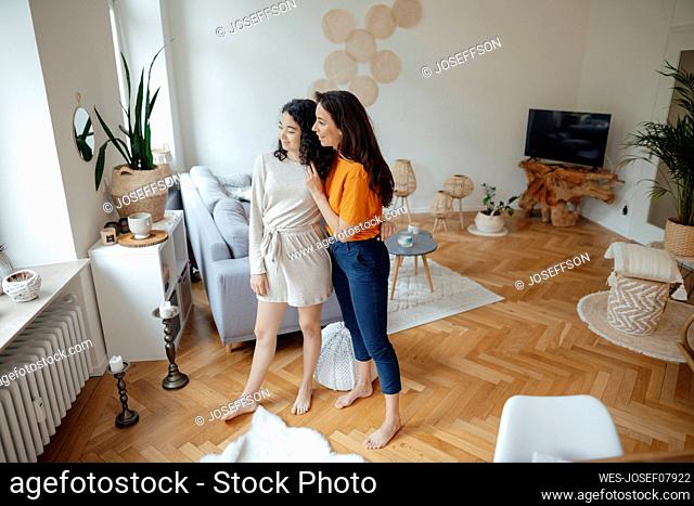 Smiling woman and daughter looking through window at home