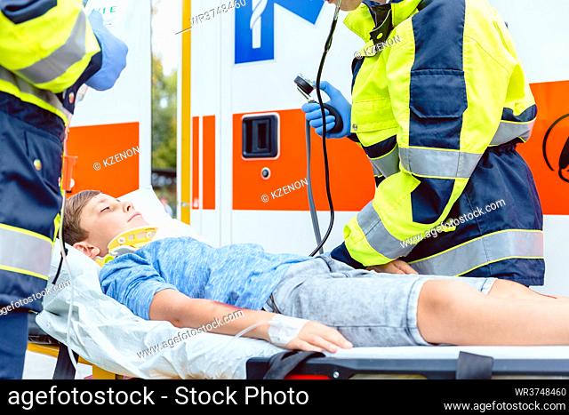 Emergency doctors putting injured boy in ambulance car
