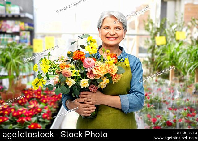 smiling senior woman with flowers at garden store