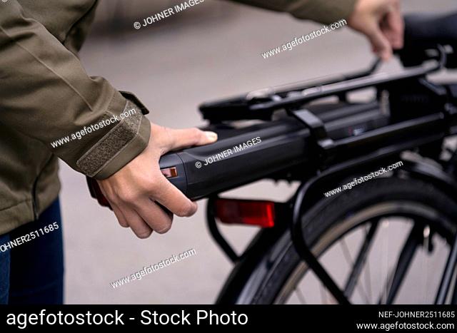 Woman fitting battery on electric bike