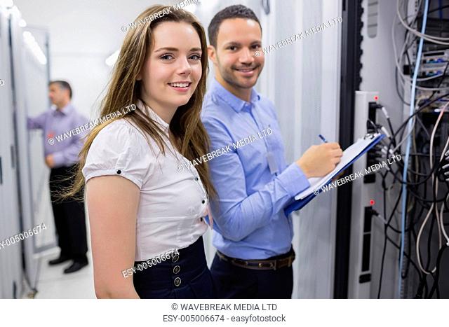 Two smiling technicians checking the servers in data center