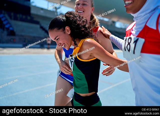 Happy female track and field athletes celebrating on track