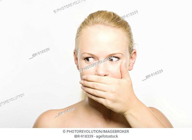 Young blonde woman covering her mouth with her hand