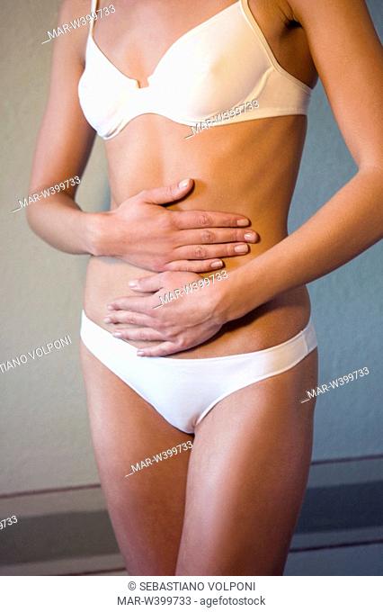 young woman standing with hands on belly