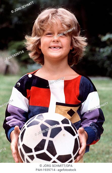 A curly-head Wayne Carpendale holding a football, pictured in July 1983. By now Wayne Carpendale is a handsome young man of 22 and appears in his first job as...
