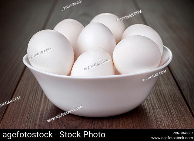 some eggs in white bowl on wooden table