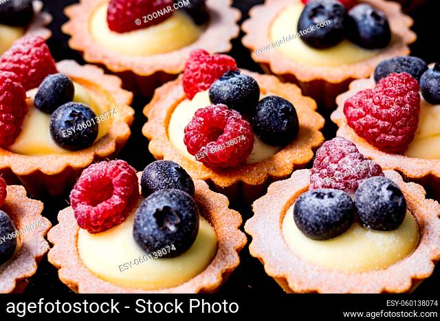 Close up tartalets with vanilla cream and fresh raspberry and blueberry berries