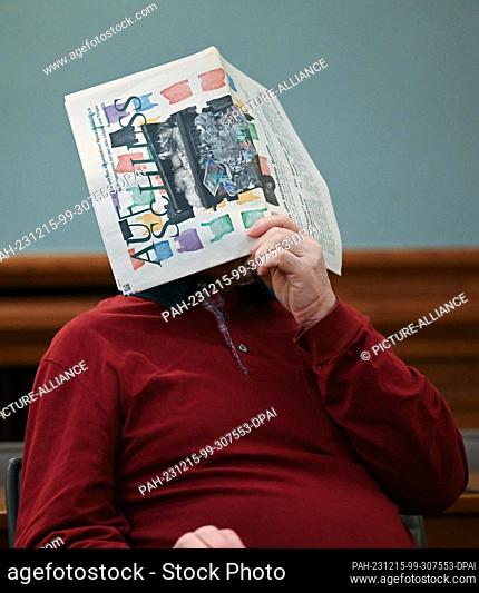 15 December 2023, Saxony, Leipzig: The accused covers his face with a newspaper. Six months after the brutal killing of a woman in Borna