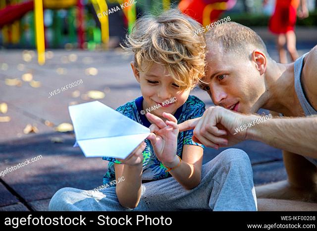 Boy with father pointing on paper airplane