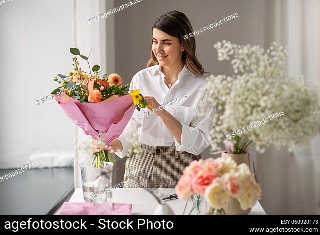 happy woman arranging flowers in vase at home