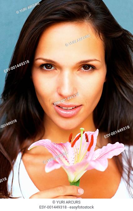 Head shot of pretty woman holding a flower looking directly in camera