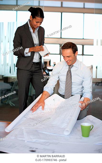 Business people reviewing blueprints together in office