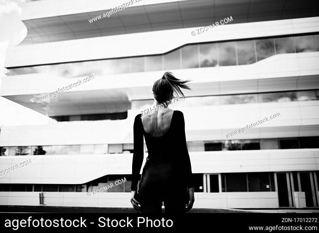 Fashion model against Zaha Hadid Dominion Tower exterior, Moscow, Russia. Black and white monochrome