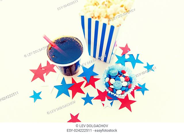 american independence day, celebration, patriotism and holidays concept - close up of coca cola cup, popcorn and candies with stars confetti decoration at 4th...