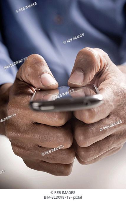 Mixed race man text messaging on cell phone