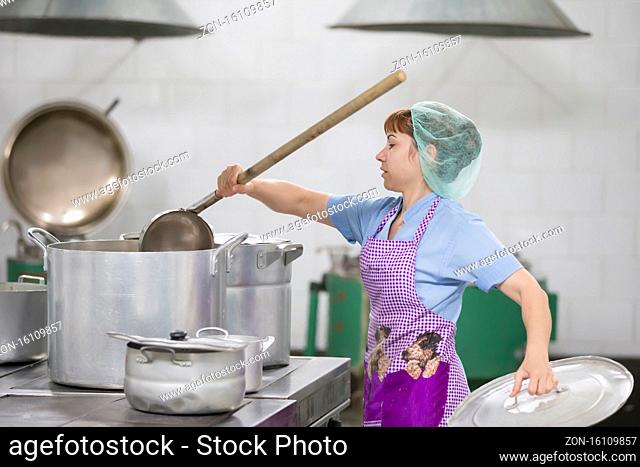 Belarus, Gomel, June 2, 2017.Industrial kitchen in the hospital. Cook prepares food. Cook with large pans and a ladle. Kitchen worker with a ladle