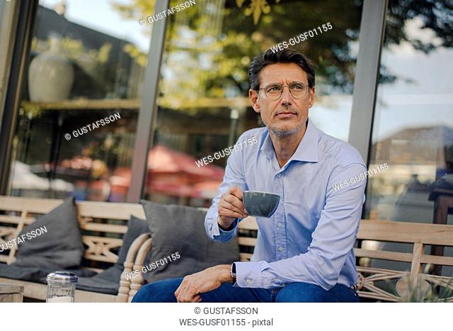 Mature businessman sitting in coffee shop, drinking coffee