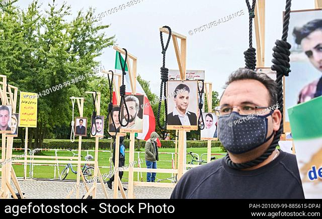 08 October 2020, Berlin: A demonstrator hangs symbolically on a gallows in front of the Reichstag. The Iranian exile community is demonstrating in front of the...