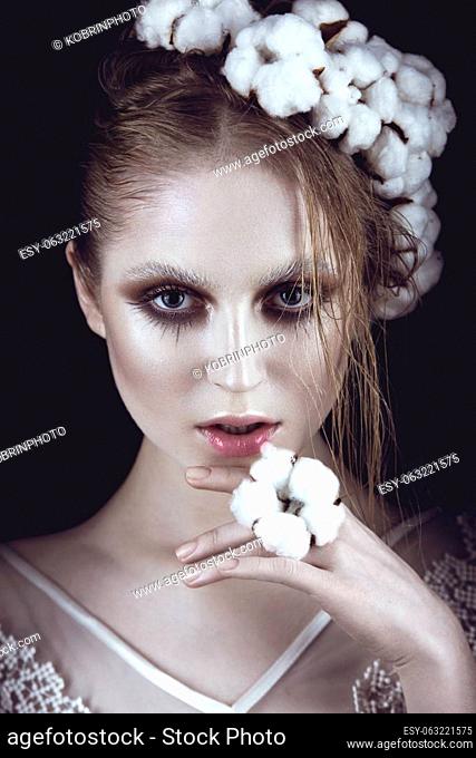 Art fashion girl with creative makeup and cotton in her hair. Beauty face. Picture taken in the studio