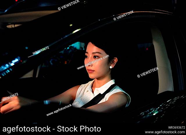 Driving a car at night young woman