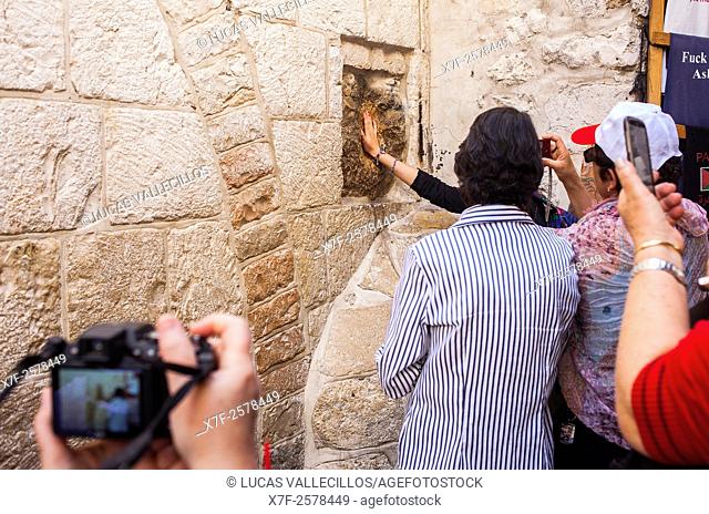 Woman inserts her hand over a handprint, Station V, Way of the cross, Via Dolorosa