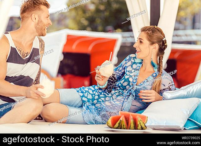Smiling young couple enjoying coconut water and watermelon