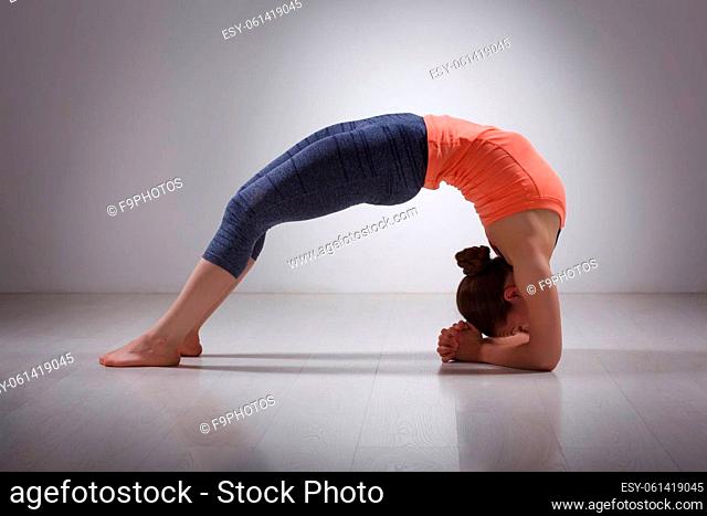 Beautiful sporty fit yogini woman practices yoga asana viparita dandasana - upward facing two feet staff pose in studio