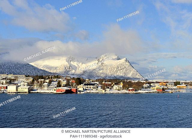 Several buildings and fishing huts from the small Vesterålen-Village Risøyhamn with the snowcapped mountains from the island Andøya in the background