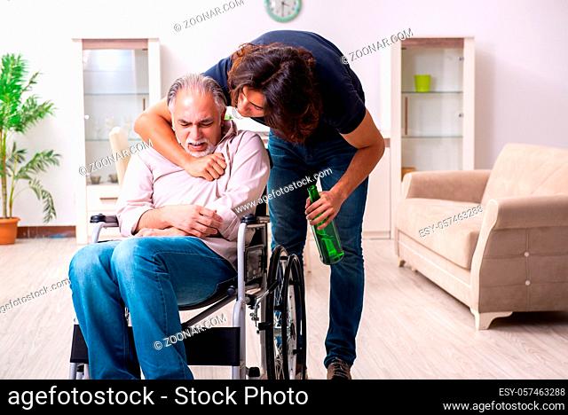 Old man in wheel-chair and bad caregiver indoors