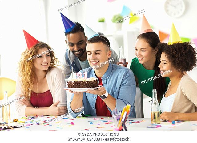 man with birthday cake and team at office party