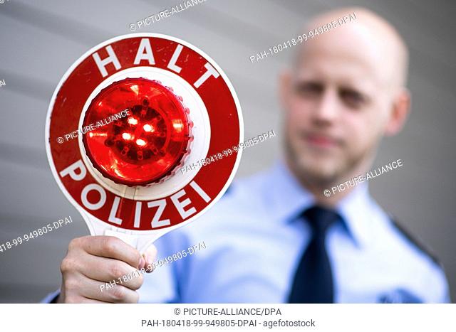 18 April 2018, Germany, Moenchengladbach: A police officer holds up a police stop sign reading 'Halt Polizei' (lit. stop police) during a press event